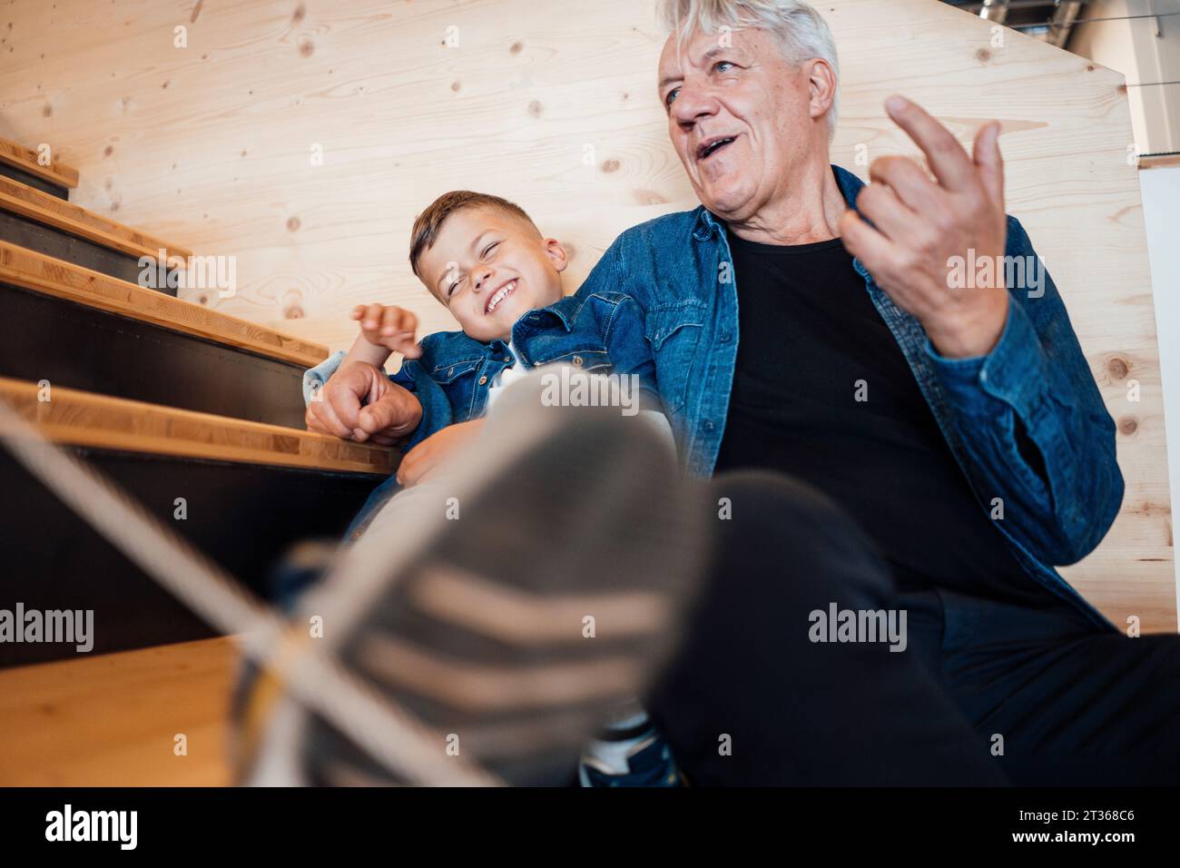 Grandson and grandfather spending leisure time sitting at home Stock Photo