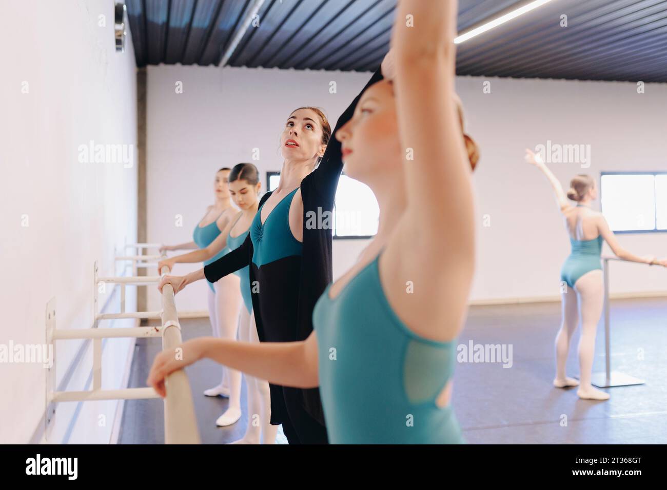 Instructor assisting ballet students in dance school Stock Photo