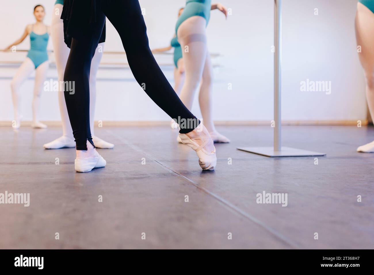 Instructor wearing ballet shoes teaching students in dance school Stock