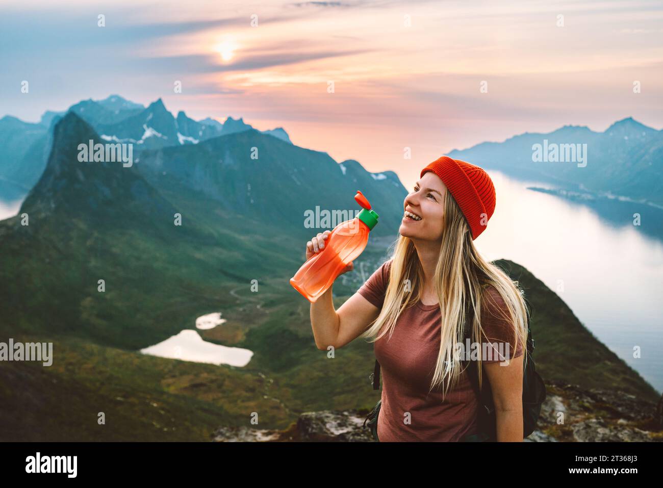 Thirsty woman hiker drinking water with plastic bottle on mountain top Travel lifestyle adventure active vacations in Norway outdoor Stock Photo