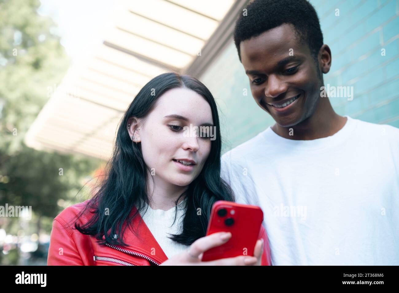 Happy young man with woman using smart phone Stock Photo