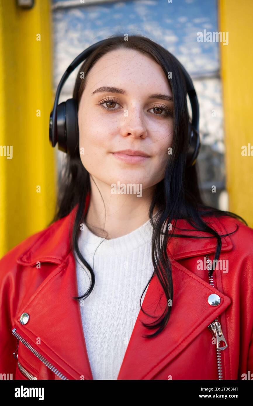 Smiling young woman wearing wireless headphones Stock Photo