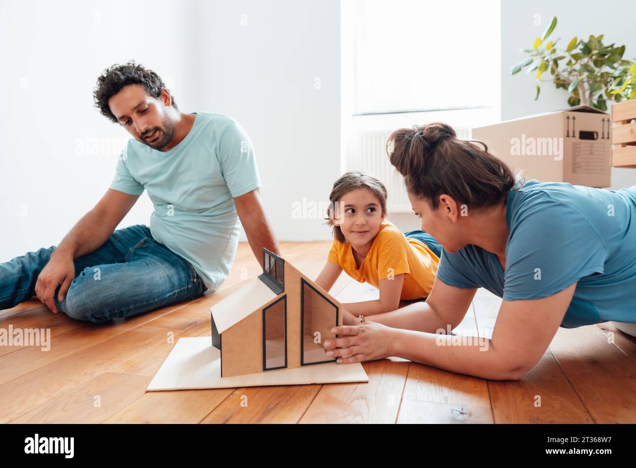 Family talking at model house on floor Stock Photo