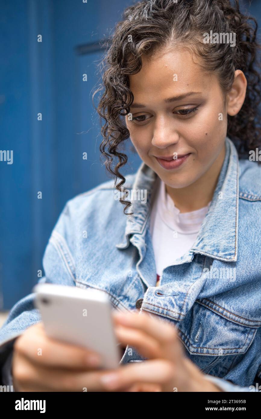 Smiling young woman using smart phone Stock Photo