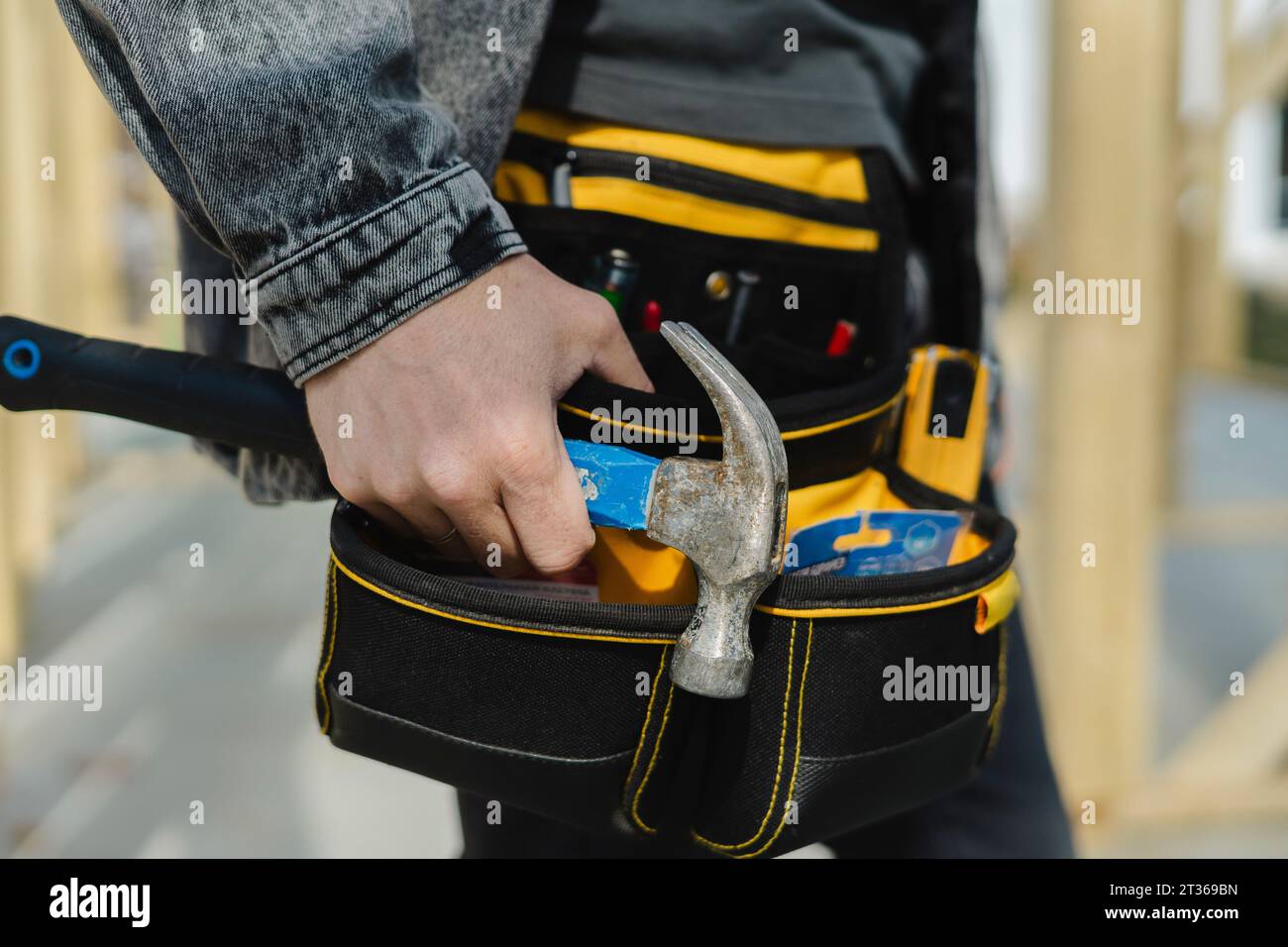 Engineer wearing tool belt holding hammer in hand Stock Photo Alamy