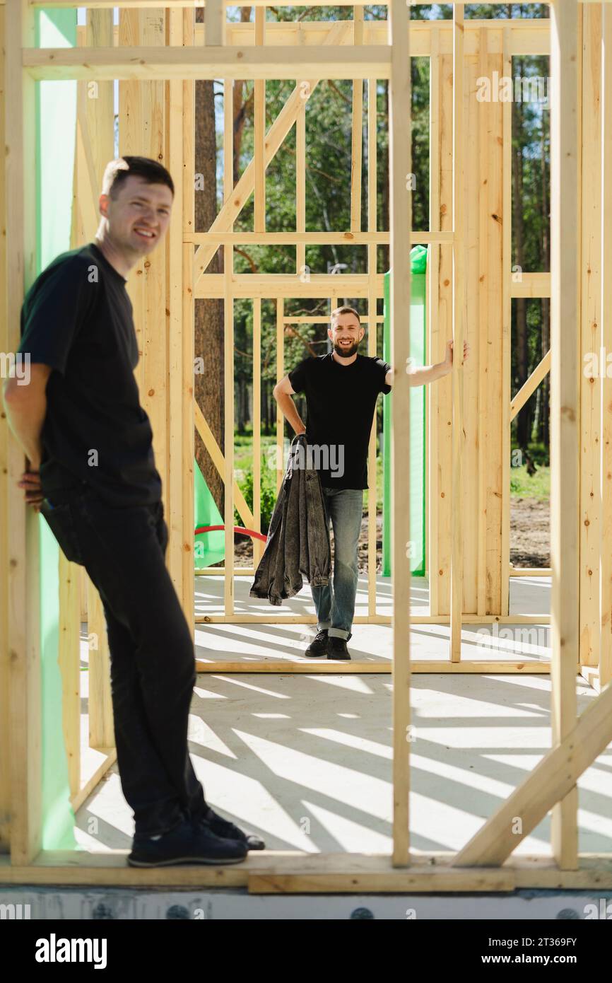 Blue-collar workers standing near construction frame on sunny day Stock Photo