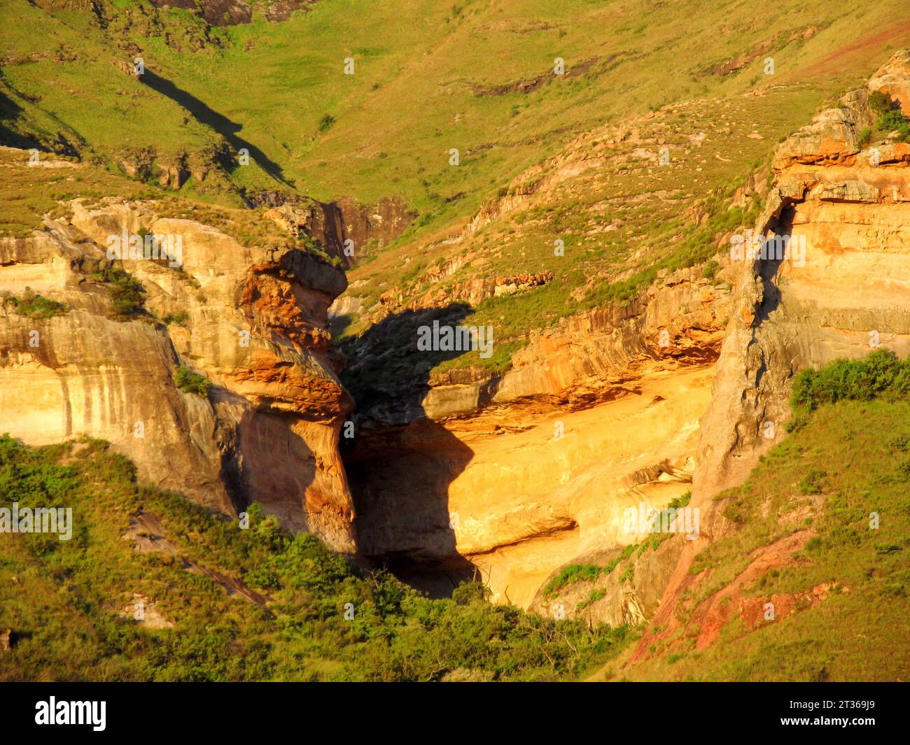 The golden cliffs and a small sandstone arch, surrounding the entrance to a narrow gorge called the Eco Ravine Stock Photo