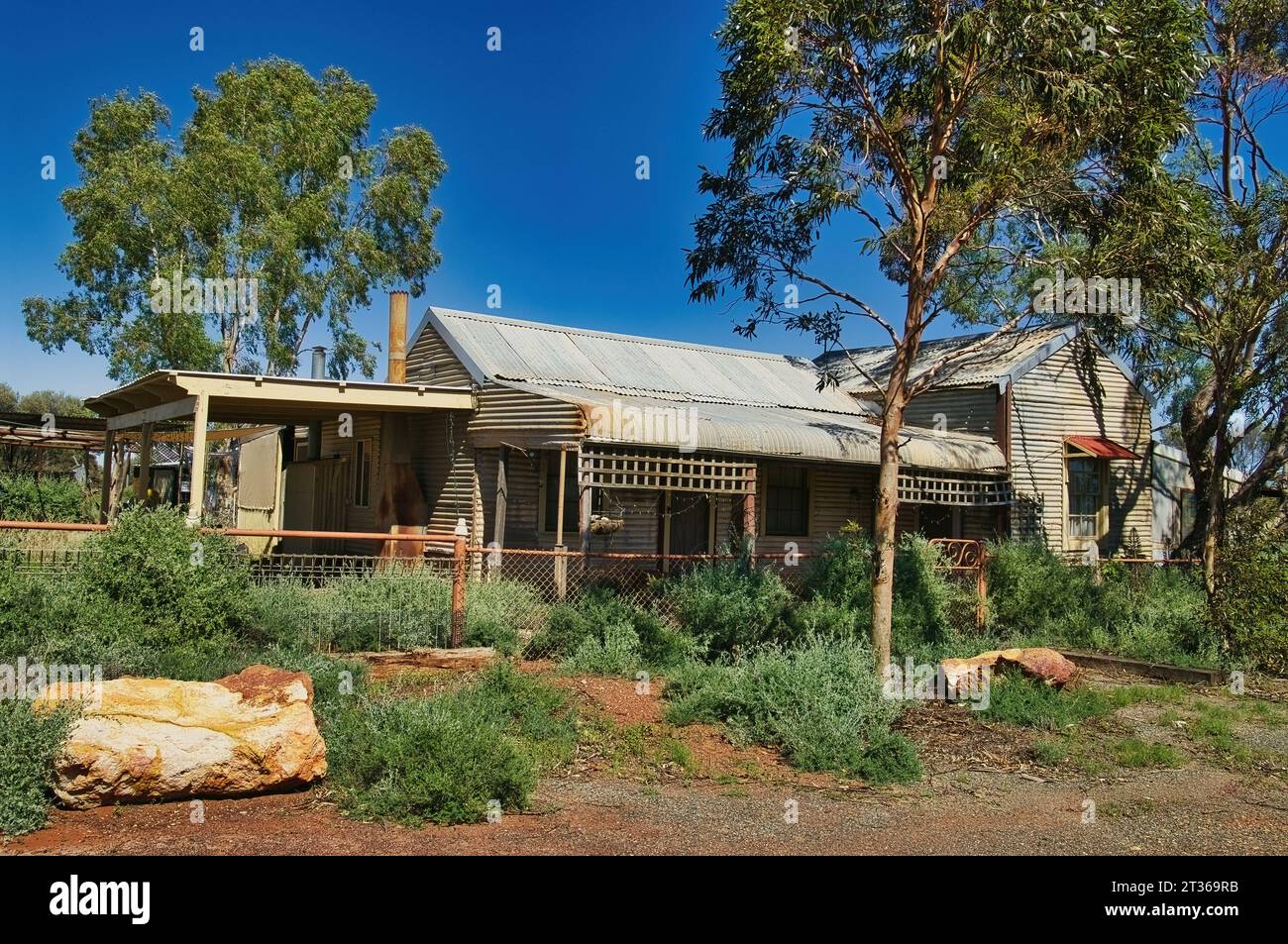 Abandoned cottage of corrugated iron and wood, with overgrown garden, in the former gold mining town of Kookynie, now a ghost town, Western Australia Stock Photo