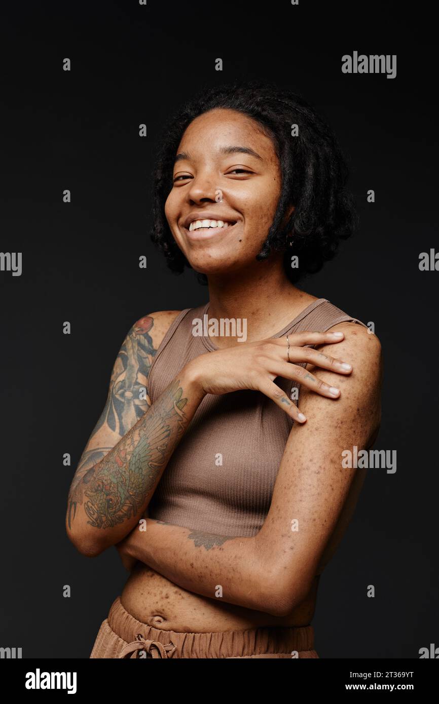 Happy woman with acne scars and tattoo against black background Stock Photo  - Alamy, image size:866x1390