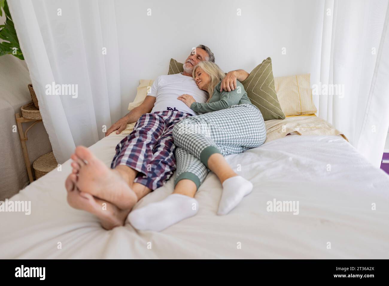 Mature couple relaxing together on bed at home Stock Photo