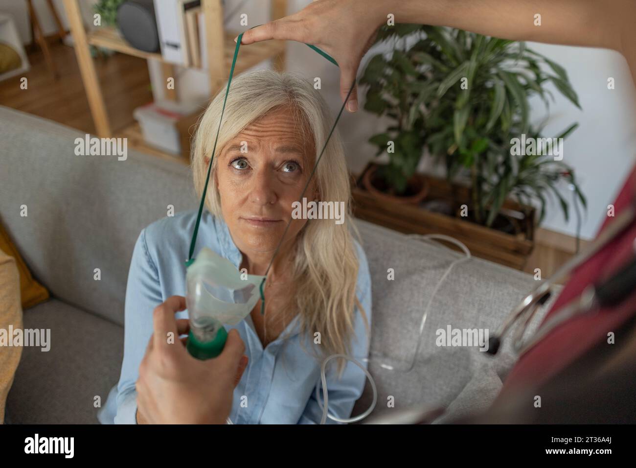 Doctor putting oxygen mask on patient's face at home Stock Photo