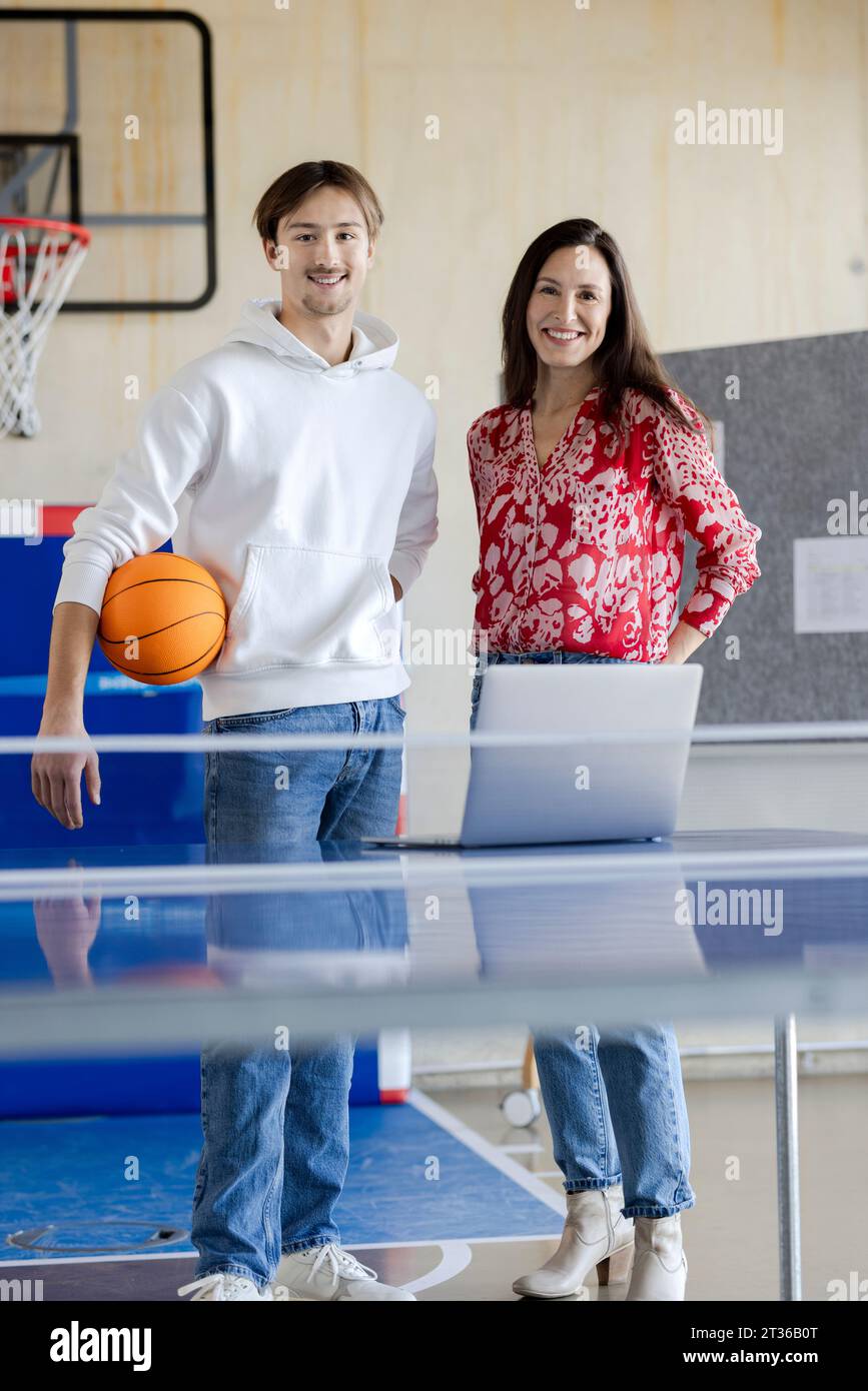 Happy young trainee standing with businesswoman in office Stock Photo