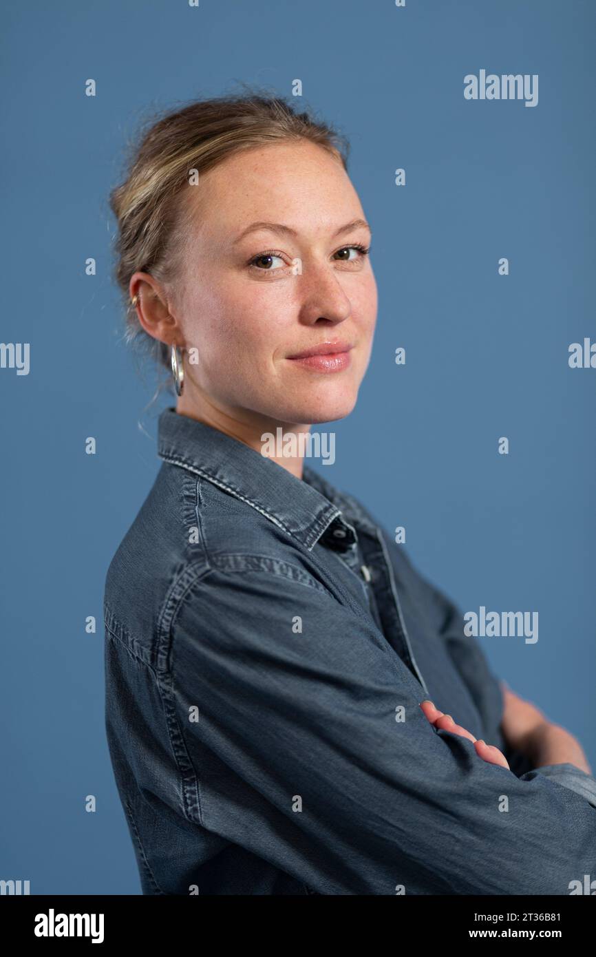 Blond woman with arms crossed against blue background Stock Photo - Alamy