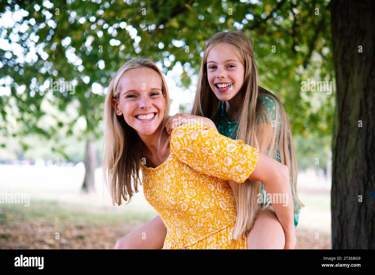 Happy woman piggybacking daughter at park Stock Photo