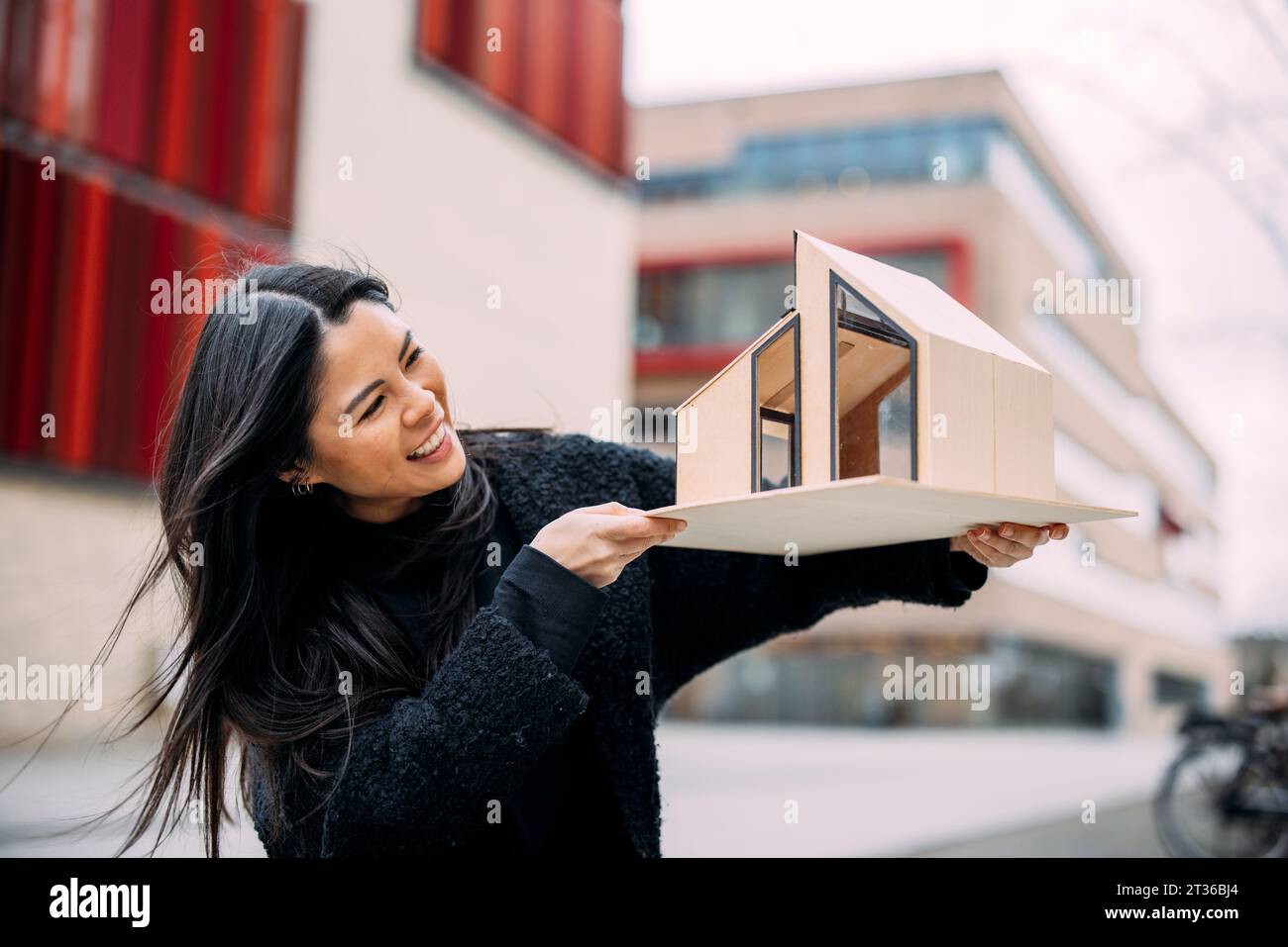 Happy architect examining house model outside office building Stock ...