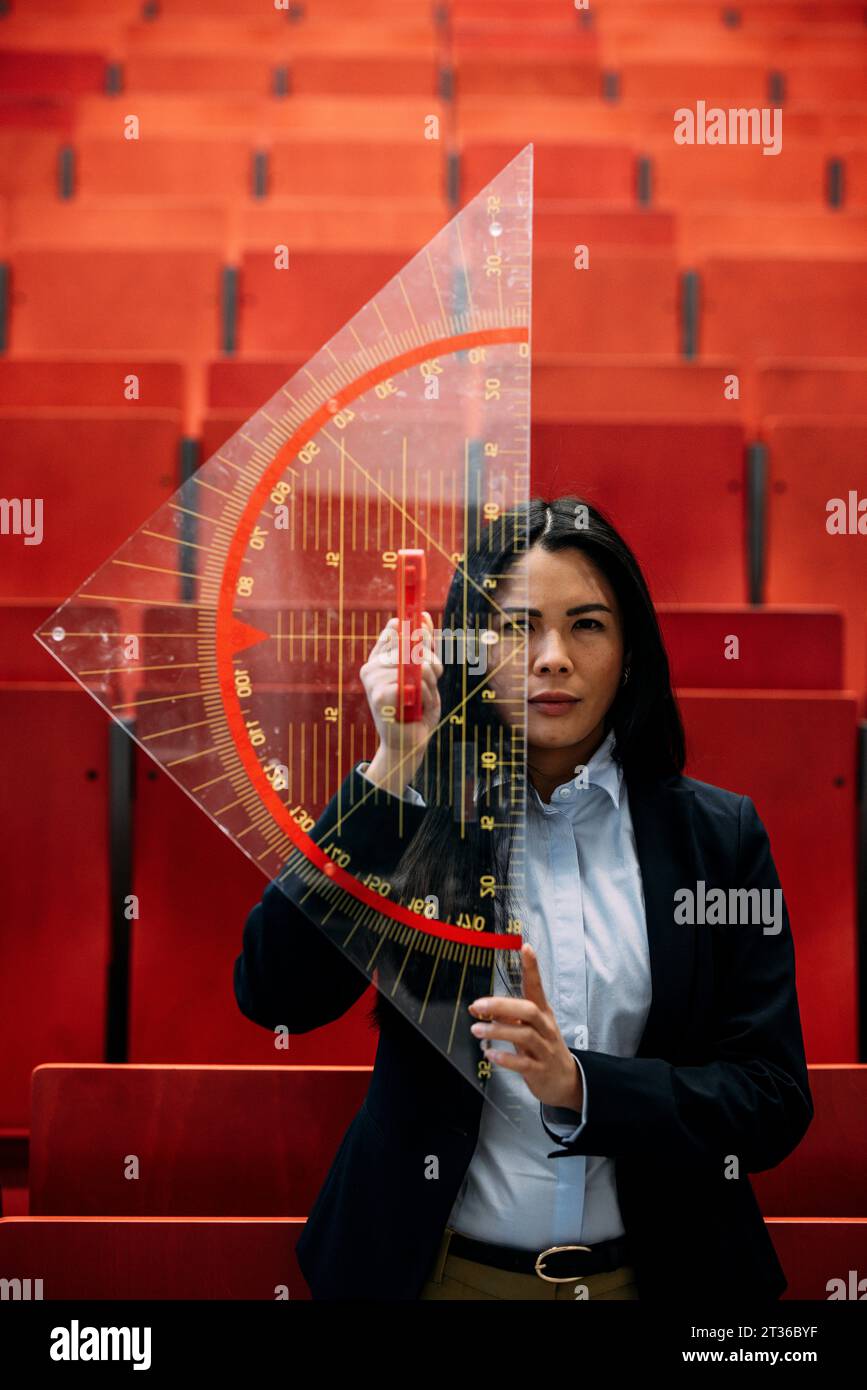 Large Protactor Confident businesswoman holding large protractor in convention center ...