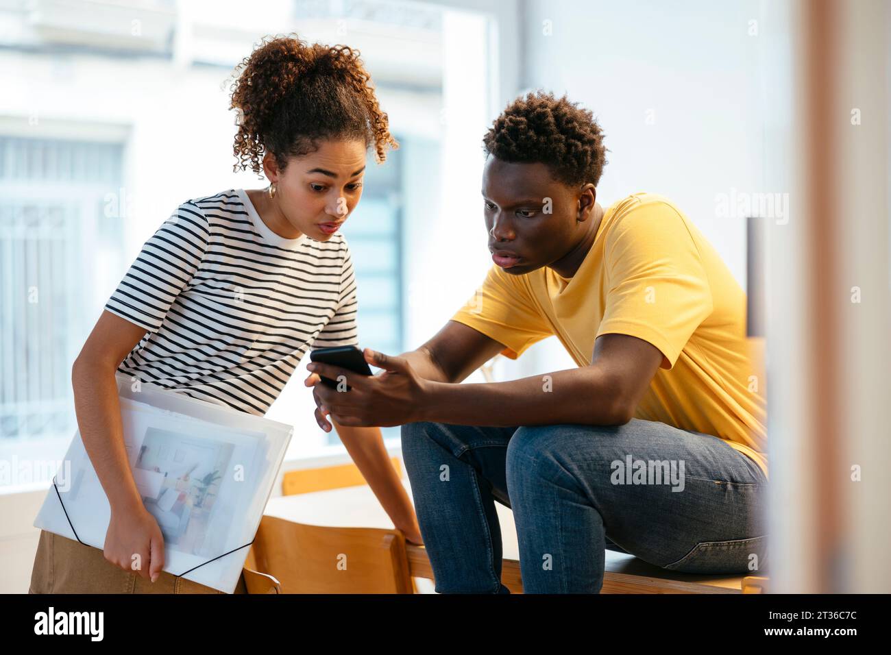 Young students using smart phone and discussing at university Stock Photo
