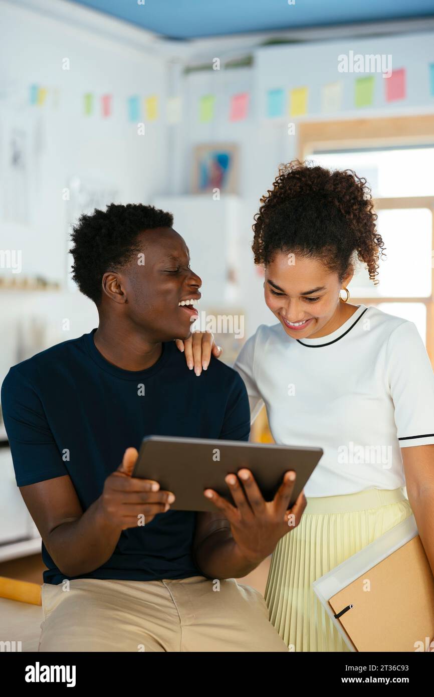 Happy young students using tablet PC together at university Stock Photo