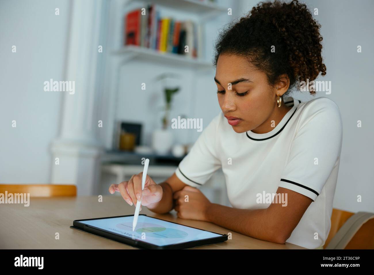 Student studying and writing on tablet PC at desk Stock Photo