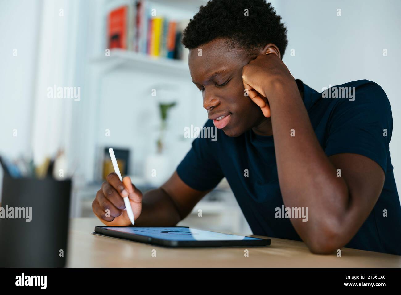 Young student studying and writing on tablet PC at desk Stock Photo
