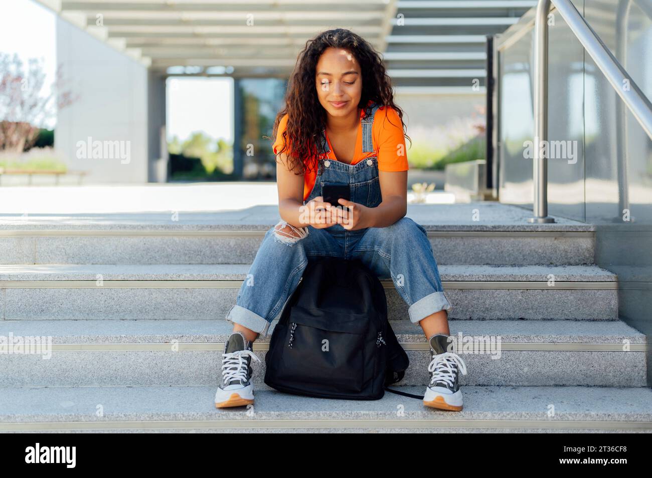 Happy student using smart phone on steps in campus Stock Photo
