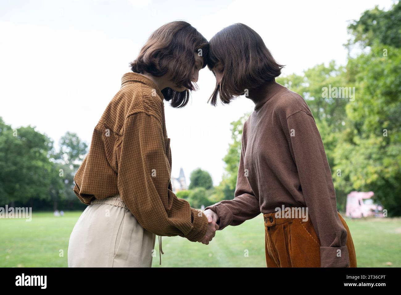 Young twin sisters holding hands at park Stock Photo - Alamy