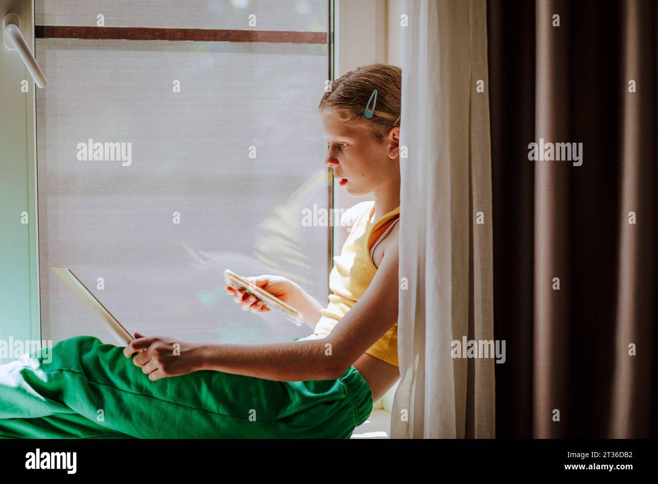 Girl with smart phone using laptop at home Stock Photo