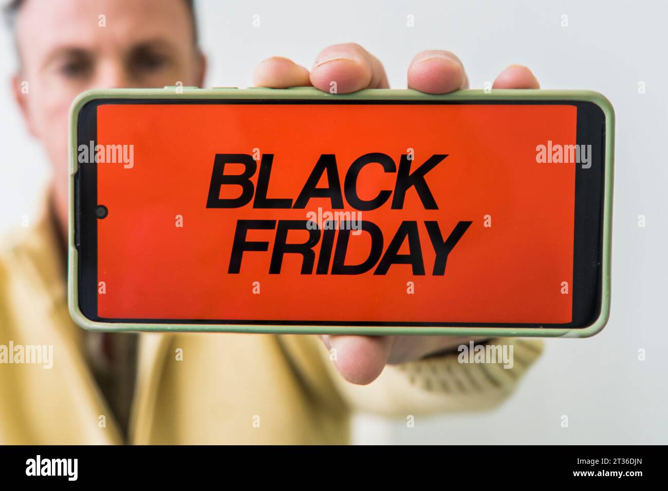 A man holding mobile phone with Black Friday advertisement on the screen. Stock Photo