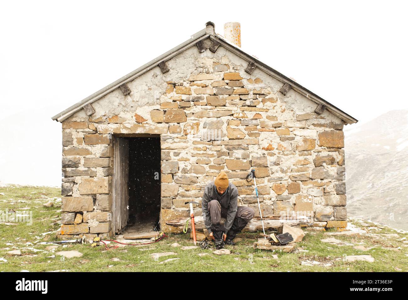 Man tying shoe near brick house on mountain Stock Photo
