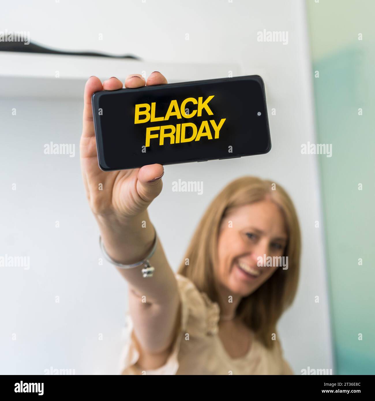 A woman showing a smartphone with Black Friday advertisement on the screen. Stock Photo