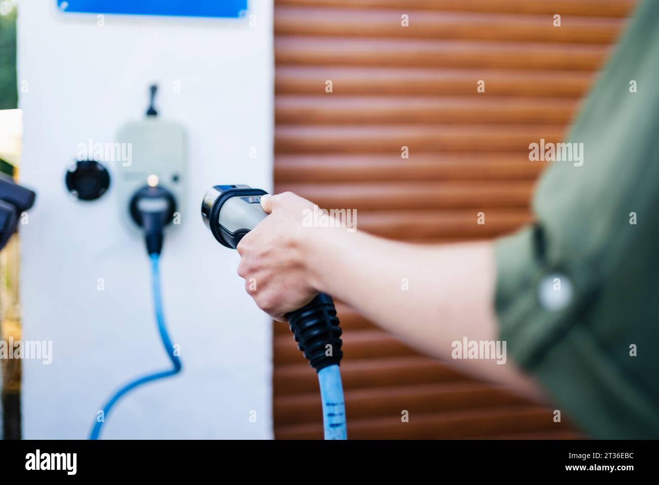 Woman holding electric charging plug at station Stock Photo