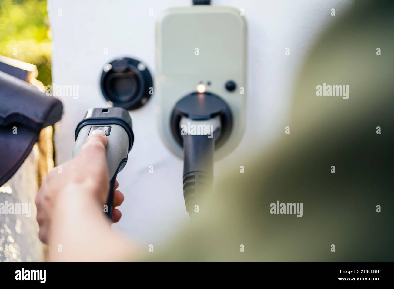 Woman holding electric plug at charging station Stock Photo