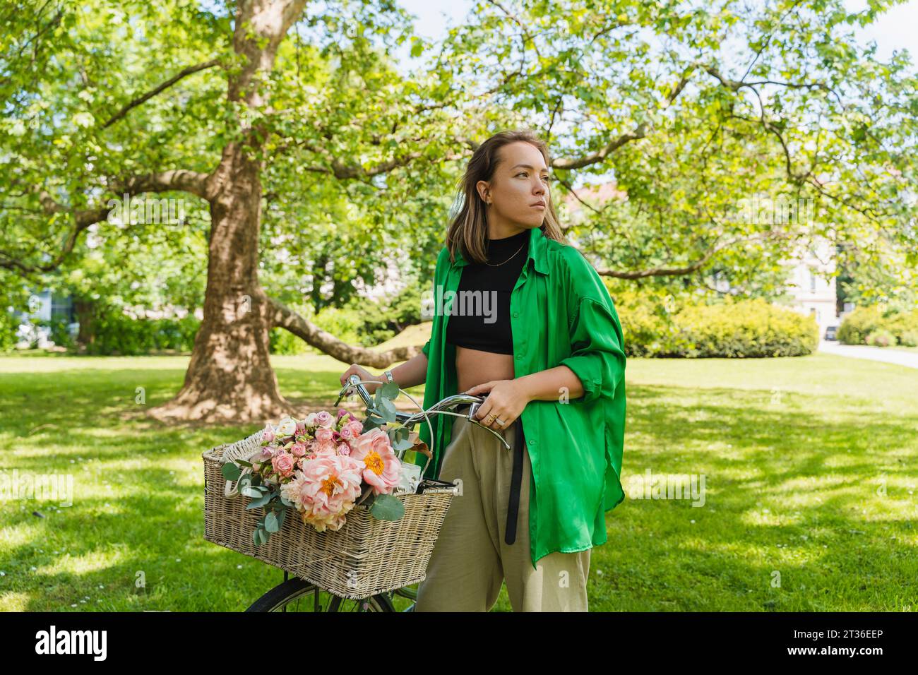 Contemplative woman with bicycle in park Stock Photo