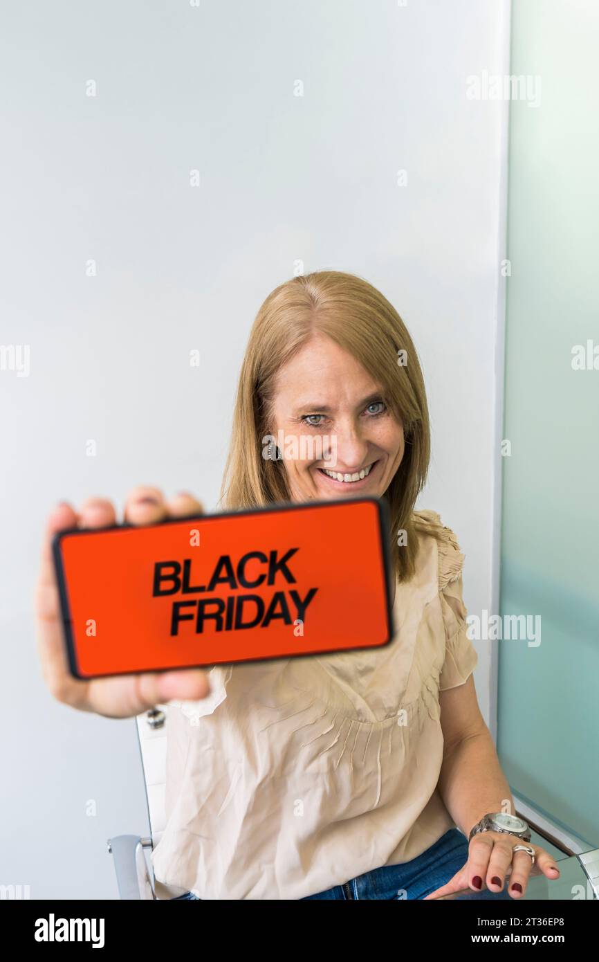A woman showing a smartphone with Black Friday advertisement on the screen. Copy space Stock Photo