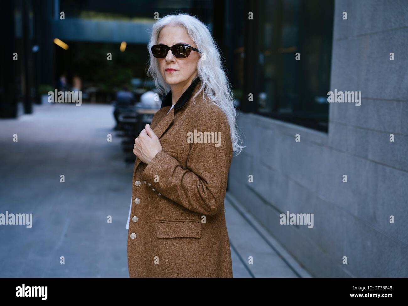 Businesswoman wearing brown jacket standing on street Stock Photo