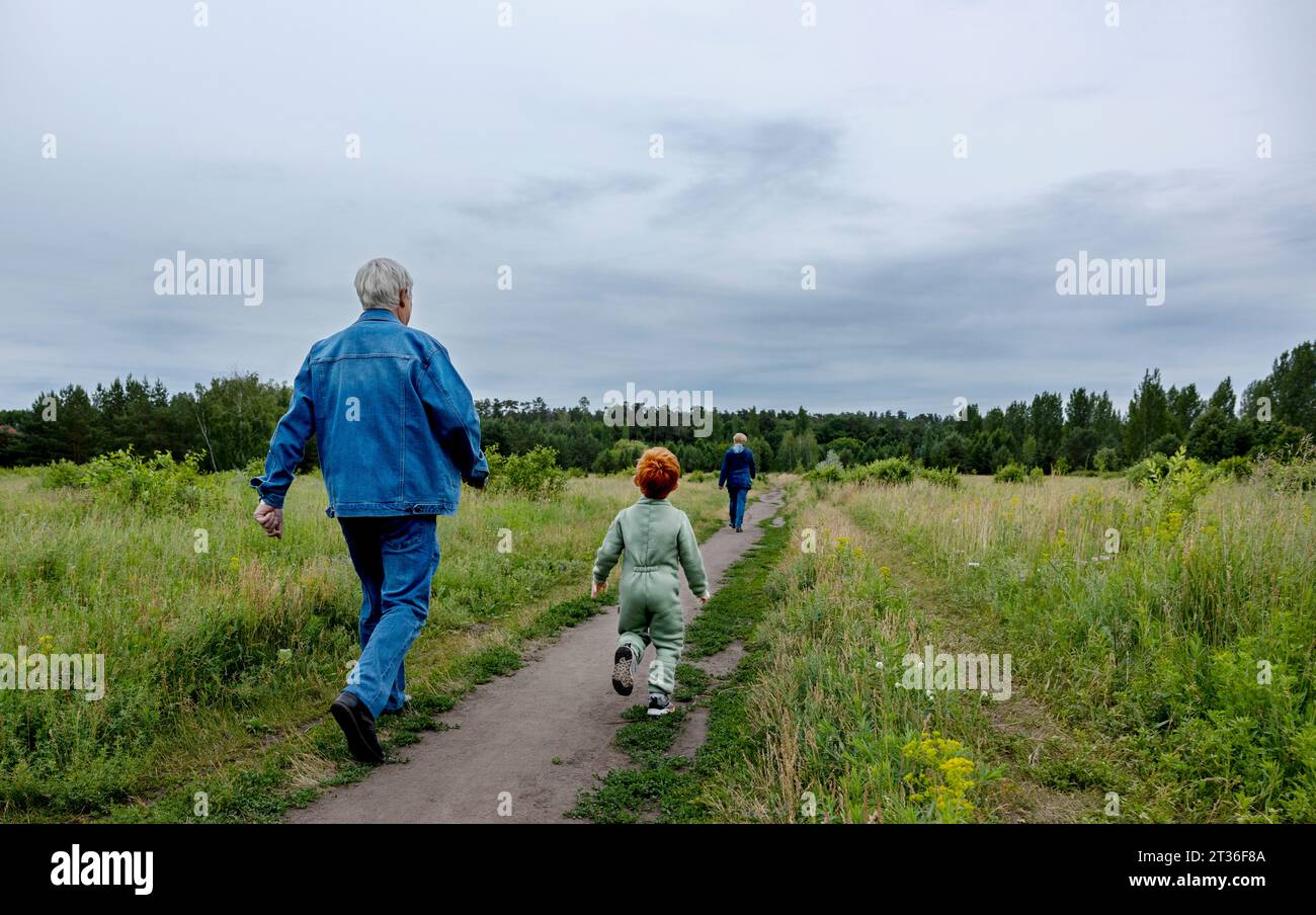 Grandparents and grandson walking on footpath at park Stock Photo