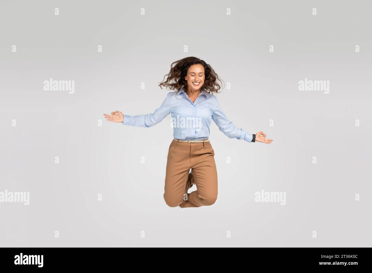 Happy calm young european woman enjoy win jump in air, joy and triumph, with closed eyes Stock Photo