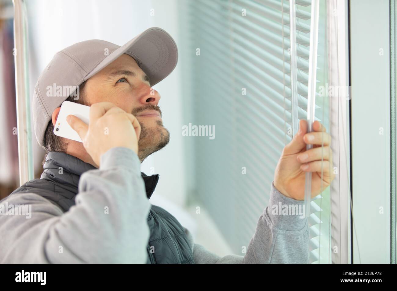 worker in uniform installing blinds on plastic upvc window Stock Photo