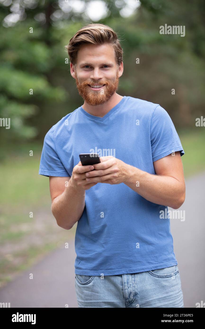 bearded man outdoors using a smartphone Stock Photo