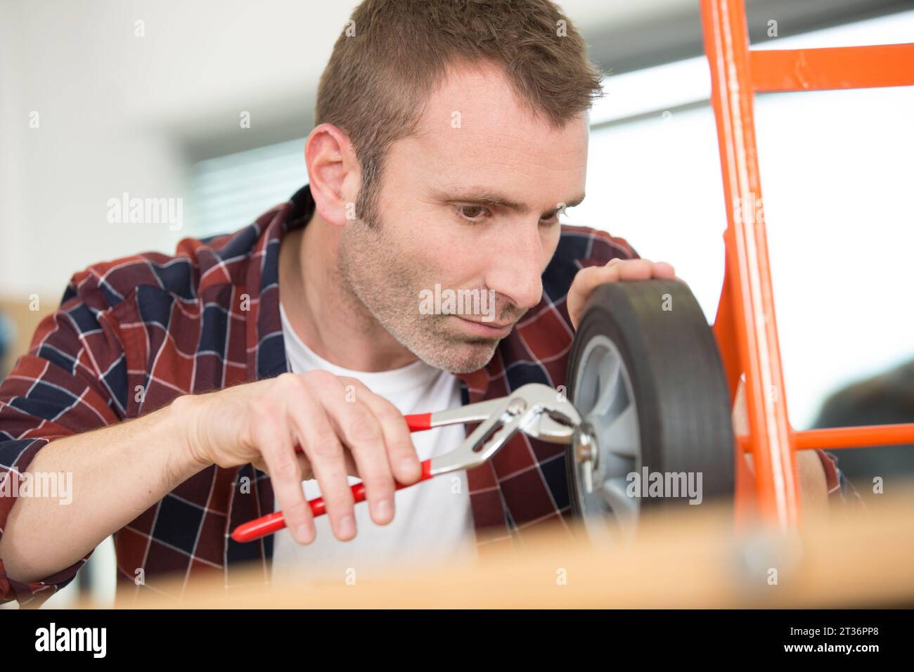 male worker is trying to fix trolley wheels Stock Photo Alamy