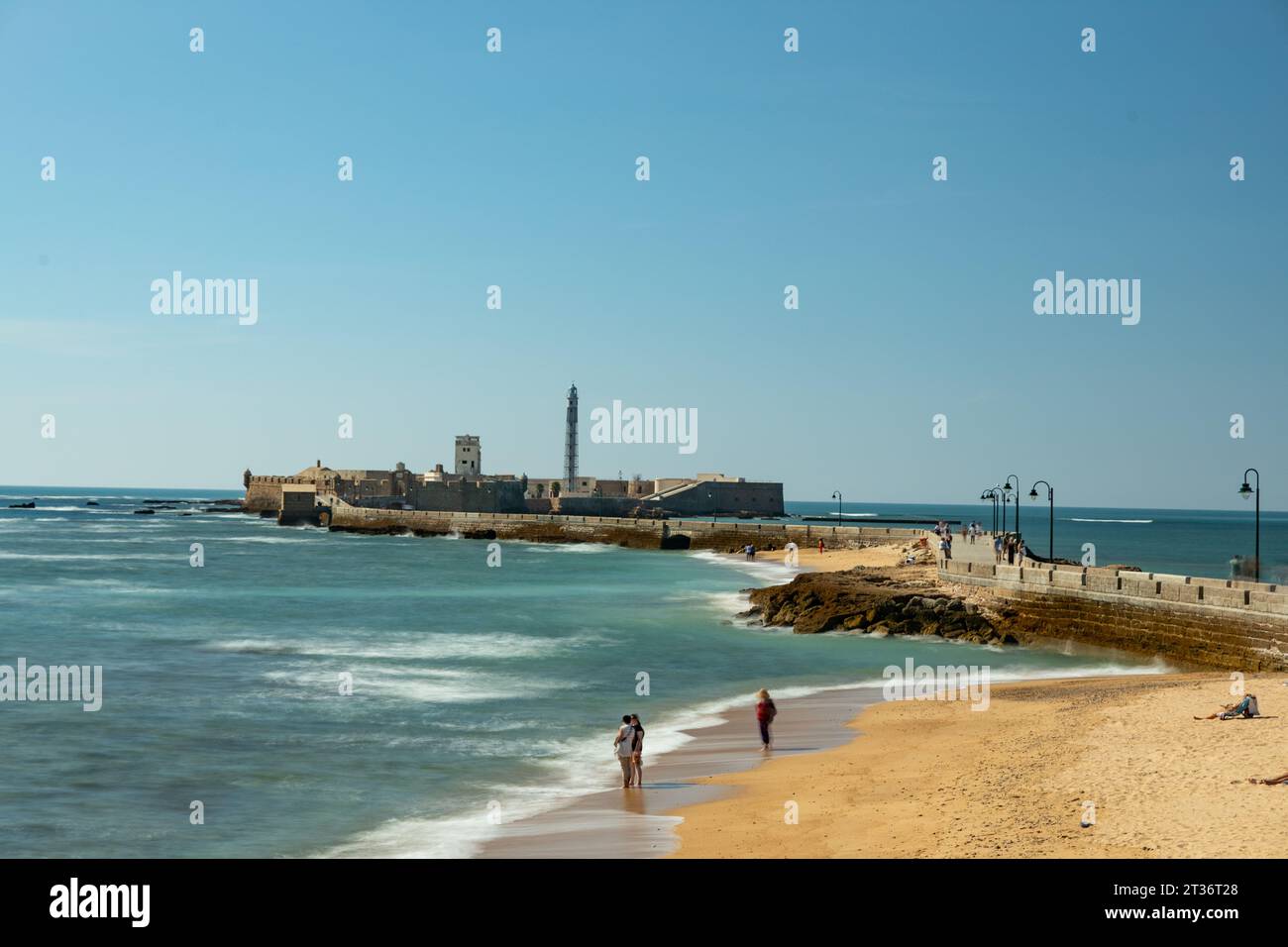 sand beach in Cadiz and view over the Paseo Fernando Quiñones way to the Castillo de San Sebastian castle Stock Photo