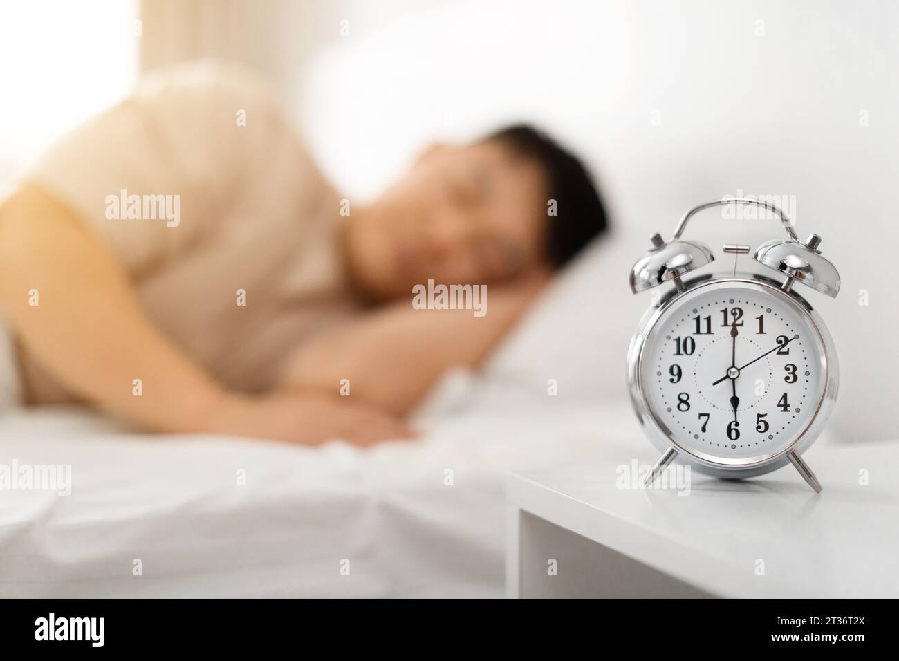 Asian man sleeping through alarm clock in the morning Stock Photo