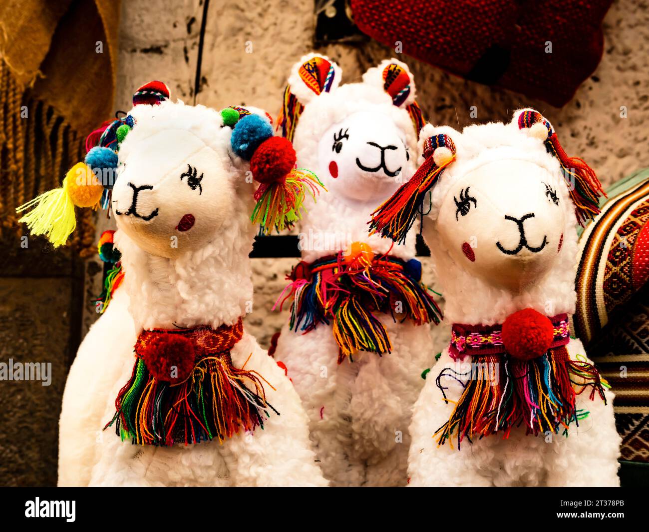 Smiling alpaca plush toys ornated with rainbow-colored bows, Pisac traditional market, Peru Stock Photo