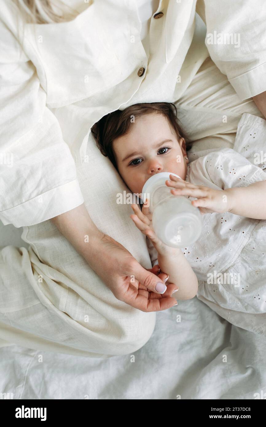 girl drinking bottle of milk laying on bed blond toddler Stock Photo - Alamy