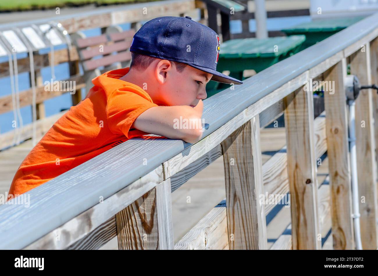 A young man in very deep thought looks out upon the ocean.. He maybe thinking of having a big boat, going out with the fishermen. Who knows. Only him. Stock Photo