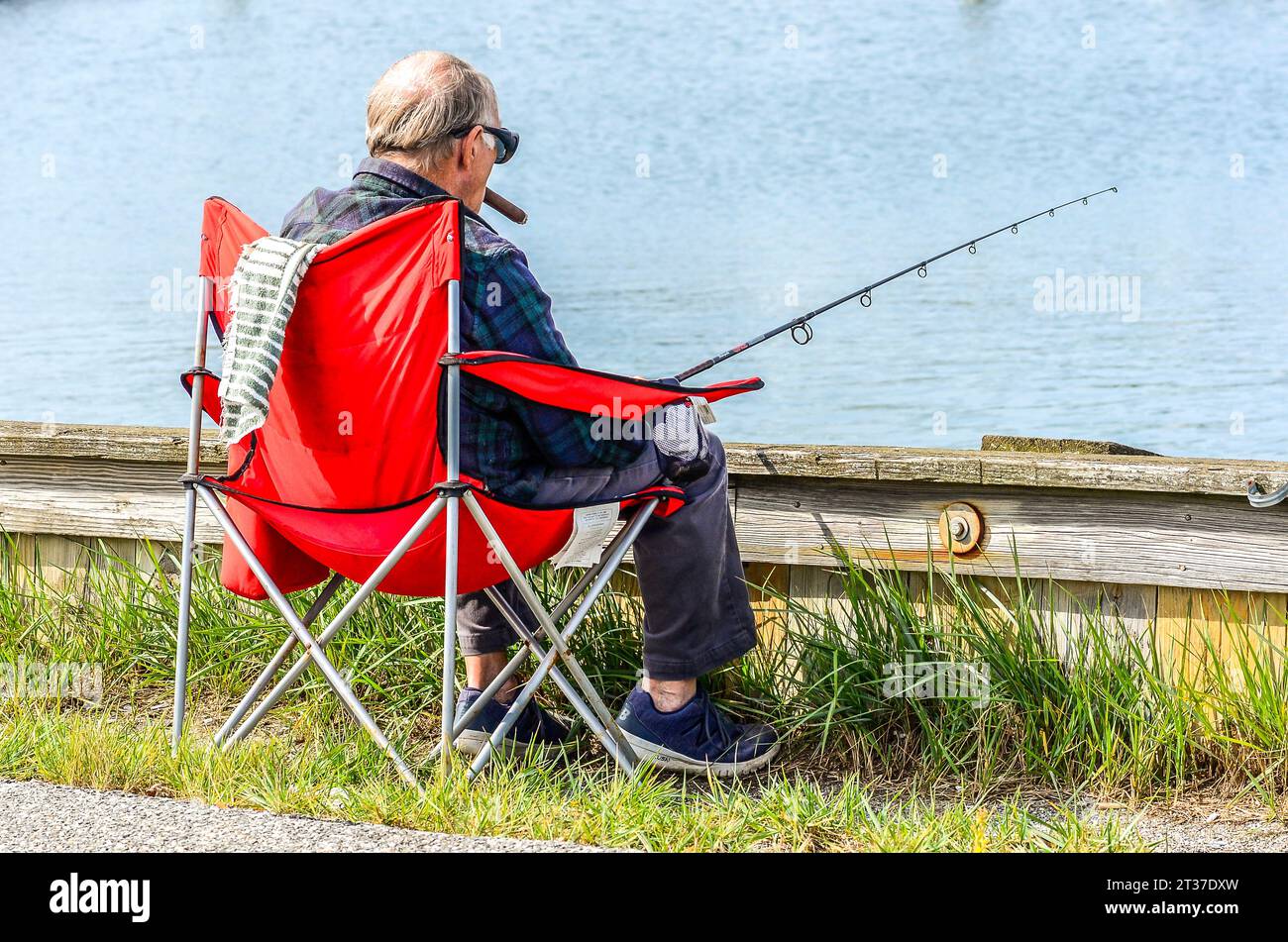 A wonderful day for fishing. All he needs chair rod and reel the right bait everything for big fish. He even has the biggest cigar he could find. Stock Photo
