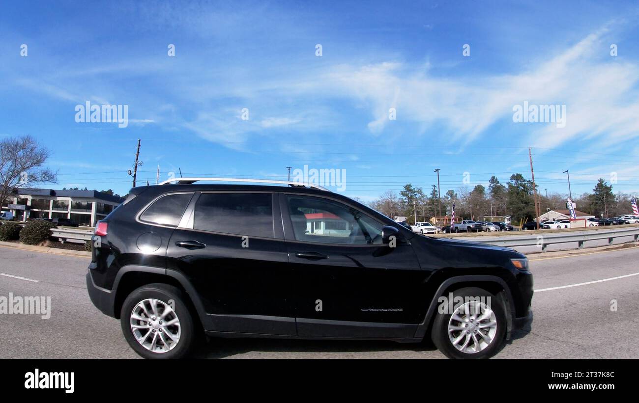 Augusta, Ga USA - 01 19 22: POV Driving street pan black newer model Jeep Cherokee in traffic Stock Photo