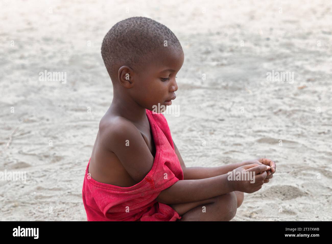 african child in the village , orphan playing in the sand, nothing around, solitude, , village in Botswana Stock Photo