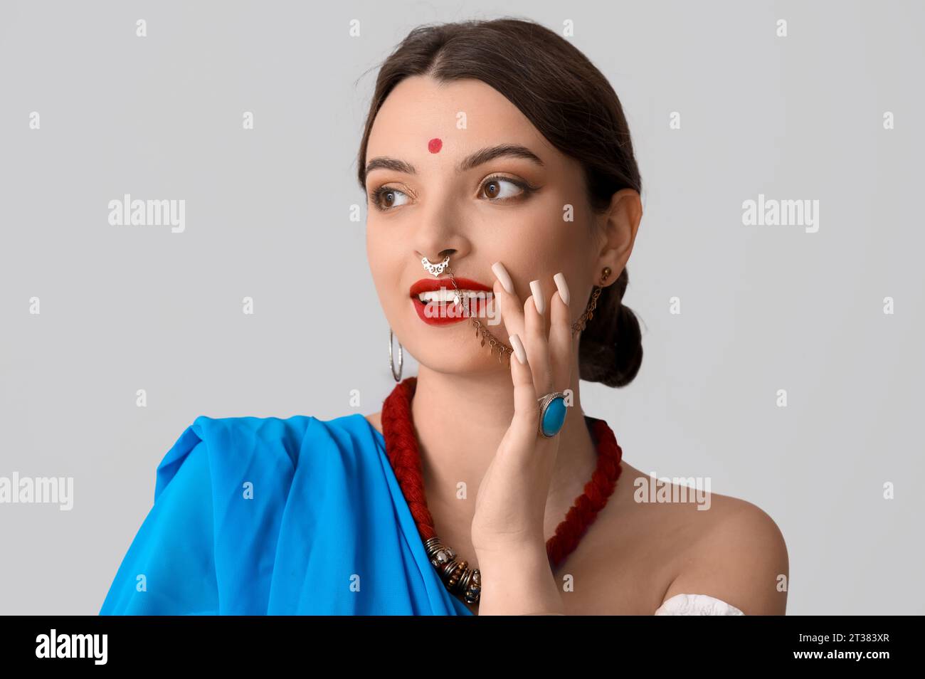 Beautiful young Indian woman in sari on grey background Stock Photo - Alamy