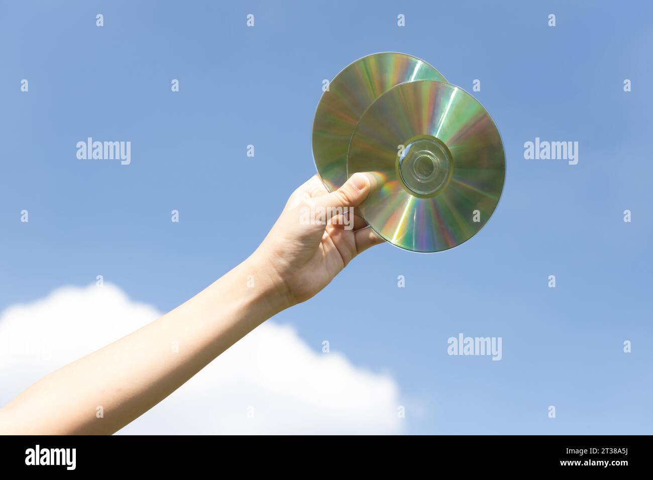 Recyclable CD disk or electric waste held in hand up on sky background